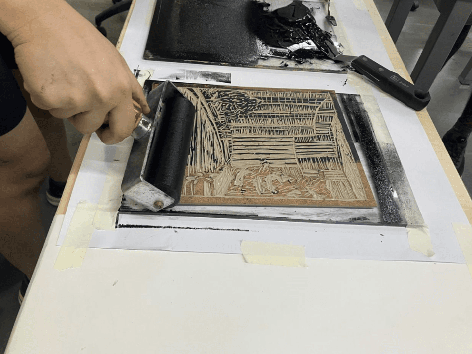 Student inking a relief block in the studio